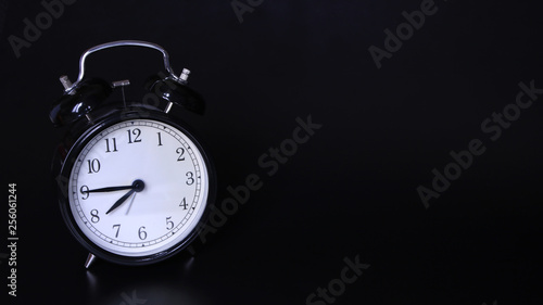 Close up image of old black vintage alarm clock. Seven'clock and forty-five minutes
