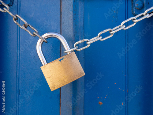 Padlock and chain fastening the door of a blue container