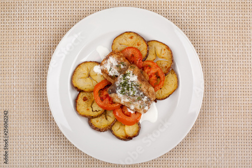 Baked potatoes in the peel sliced with tomato and grilled meat in a white sauce.