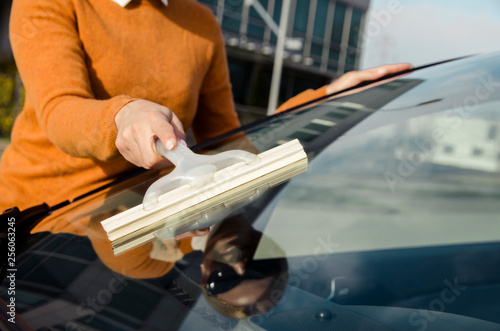 Closeup woman cleaning windscreen of a car 