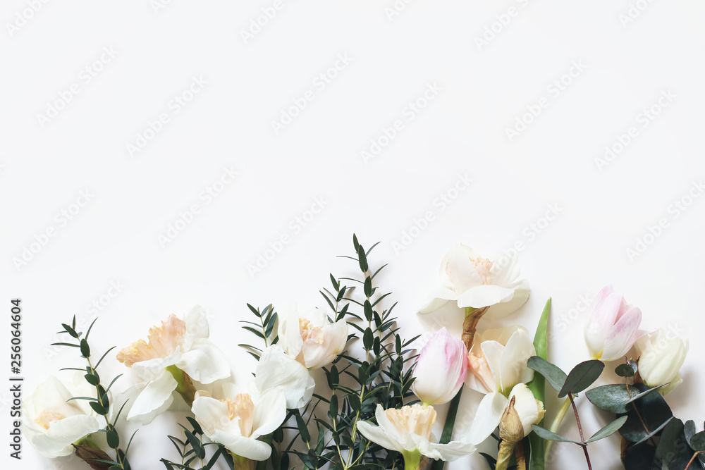 Spring, Easter styled composition with pink tulips, narcissus, daffodils flowers and eucalyptus branches isolated on white table background. Empty space. Floral frame, web banner. Top view.