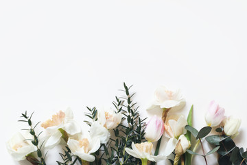 Spring, Easter styled composition with pink tulips, narcissus, daffodils flowers and eucalyptus branches isolated on white table background. Empty space. Floral frame, web banner. Top view.