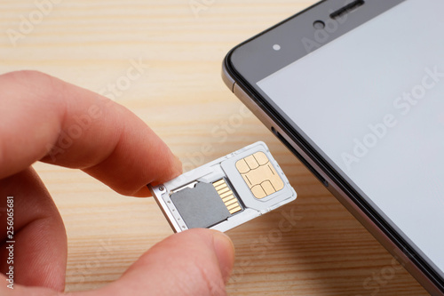 Man inserting tray for SIM card and micro SD memory card to the mobile phone. Upgrading memory in a mobile phone