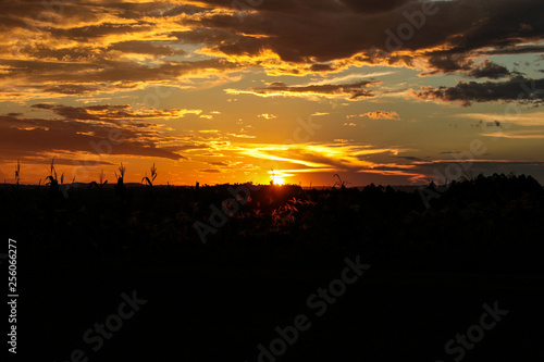 pôr-do-sol no horizonte com nuvens escuras e cores alaranjado amarelo e cinza