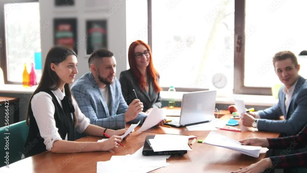 Business concept. A working team having a conference. A woman with a pony tail brings the documents and the team looking at it Business concept. A working team having a conference. A woman with a pony tail brings the documents and the team looking at it