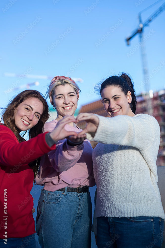 Obraz premium Girls teenagers in summer in the park in the fresh air. Gesture hands show the heart of love. Dressed in casual clothes.