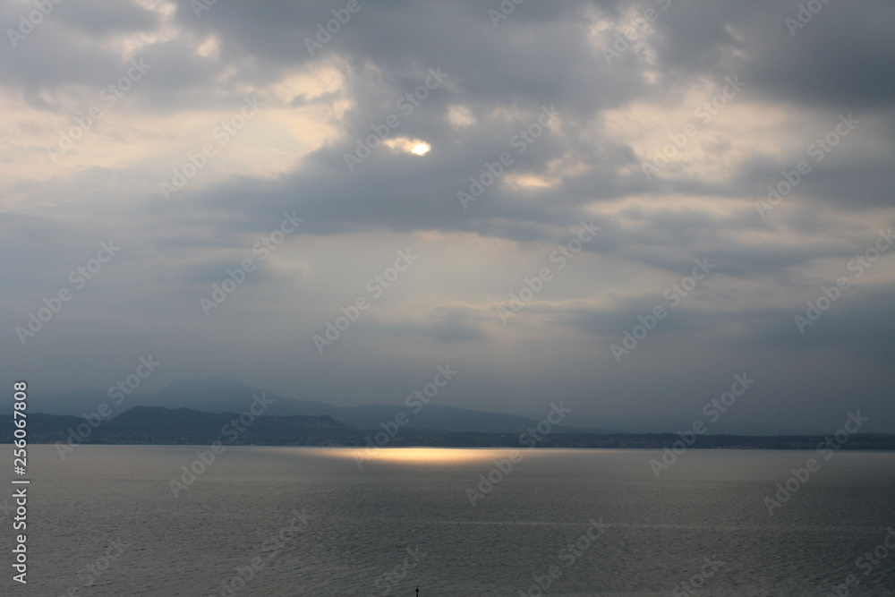 The sun breaking through the clouds over lake Garda Italy The sun breaking through the clouds over lake Garda Italy