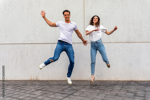 Happy couple in love jumping against grey wall. © 2Design