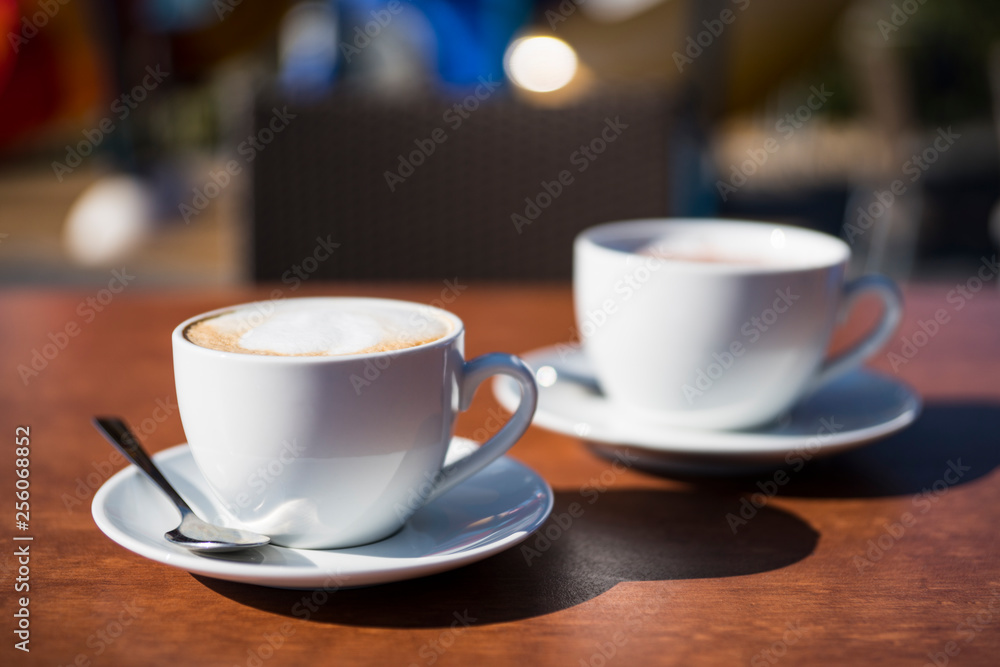two white cup and saucers with cappucciono two white cup and saucers with cappucciono