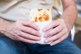 man holding a wrap, bread, piadina, against white blur background