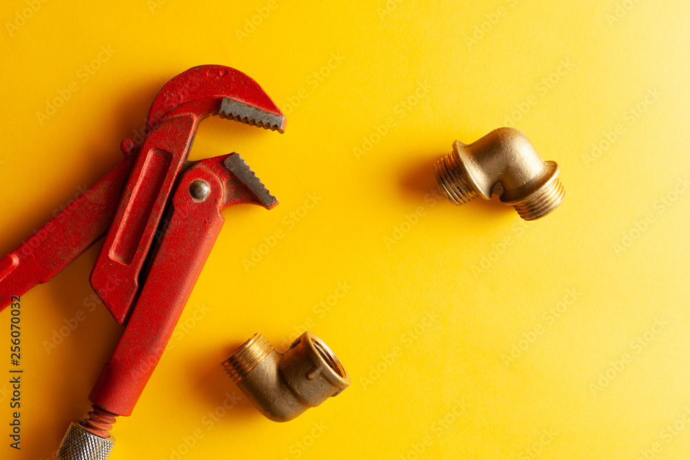 A monkey wrench on the yellow background with some fitting connectors. for design and decoration A monkey wrench on the yellow background with some fitting connectors. for design and decoration