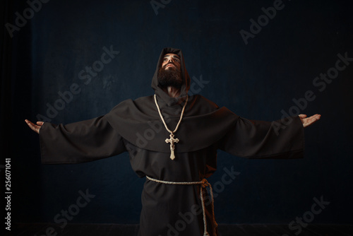 Fotografia, Obraz Monk in black robe with hood kneeling and praying