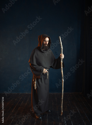 Photography Medieval monk in robe with hood rests on a stick