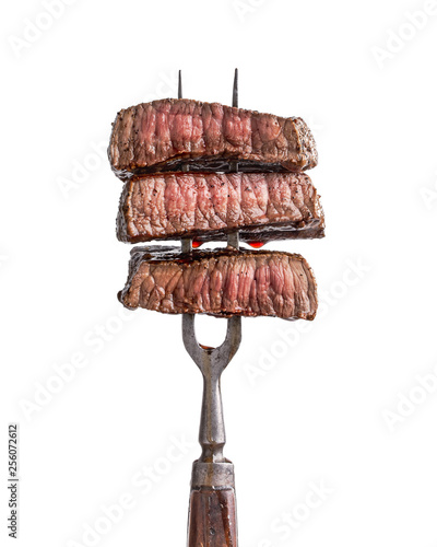 Slices of beef steak on vintage fork isolated on white photo