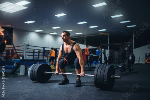 Male powerlifter starting deadlift barbell in gym