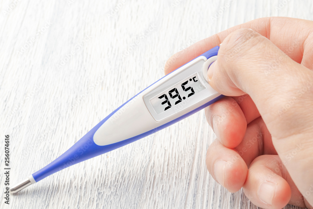 Obraz premium White-blue thermometer with a high temperature of 39.5 degrees Celsius in hand