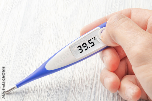 White-blue thermometer with a high temperature of 39.5 degrees Celsius in hand photo