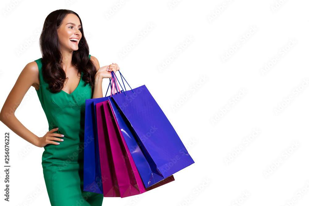 Happy young woman wearing green dress standing isolated over white background, carrying shopping bags. satisfied girl after successful shopping in the mall. copy space. sale. - Image 