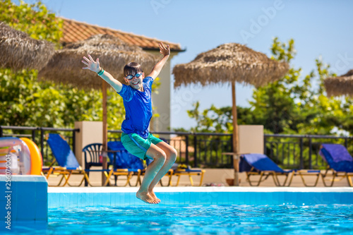 Little cheerful boy jumping to the pool and making water splash, enjoying time in the refreshing water © levranii