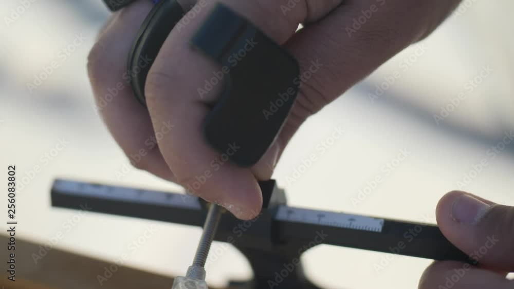 Close-up of hands fixing and adjusting the settings on a modern bow for archery Close-up of hands fixing and adjusting the settings on a modern bow for archery