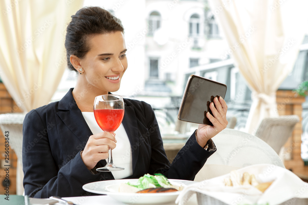 She is always working. Candid image of a beautiful smiling businesswoman using digital tablet in the cafe She is always working. Candid image of a beautiful smiling businesswoman using digital tablet in the cafe