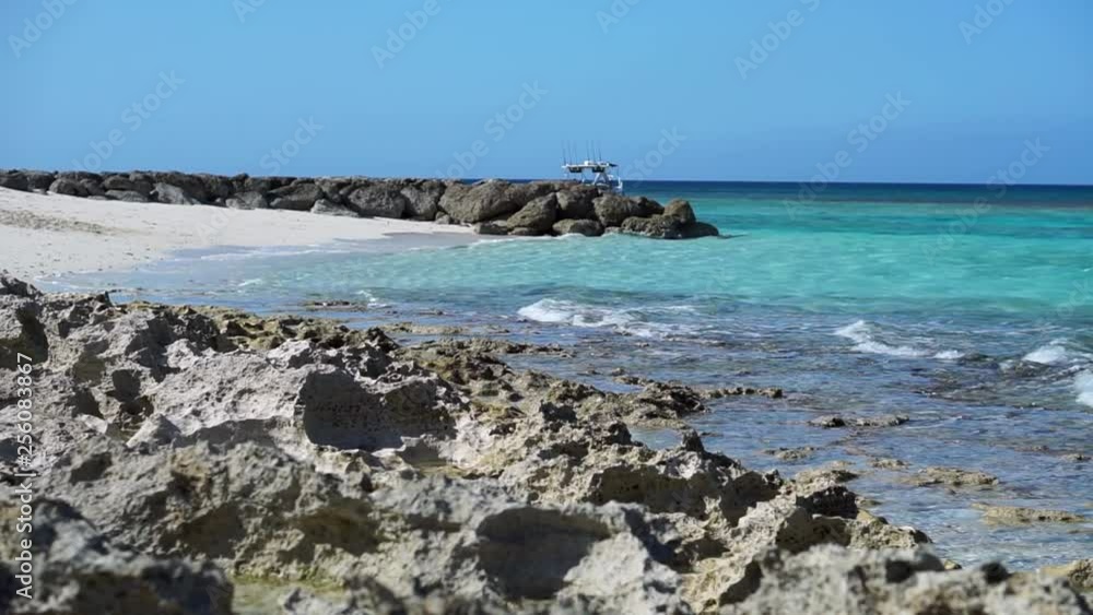 Coral foreground of a Bahamas beach bay with boat slowing drifting around in the background Coral foreground of a Bahamas beach bay with boat slowing drifting around in the background