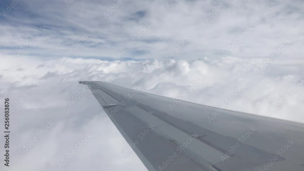 Time lapse looking out the window of a passenger jet flying through the thick white fluffy clouds Time lapse looking out the window of a passenger jet flying through the thick white fluffy clouds