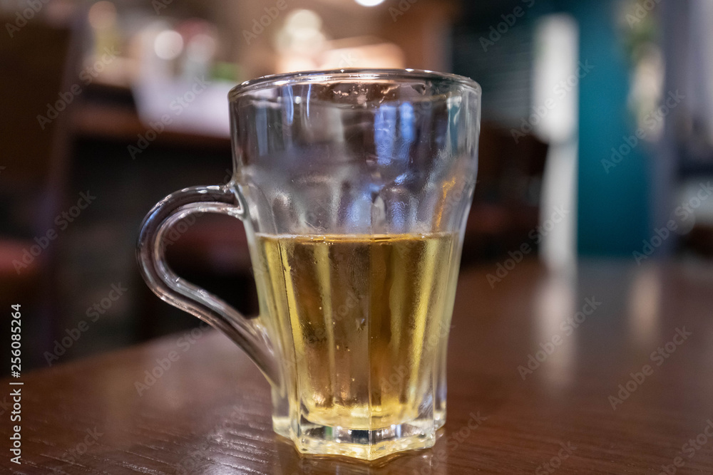 Glass half empty or half full sits on wooden table with blurred background