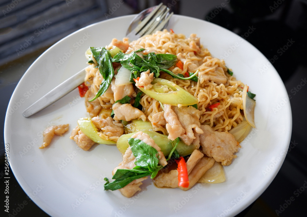 Instant noodle stir fried chicken chili pepper and basil leaf on white plate top view