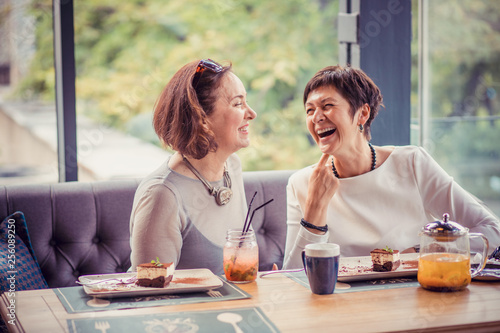 Laughing aged women enjoying meeting in cafe
