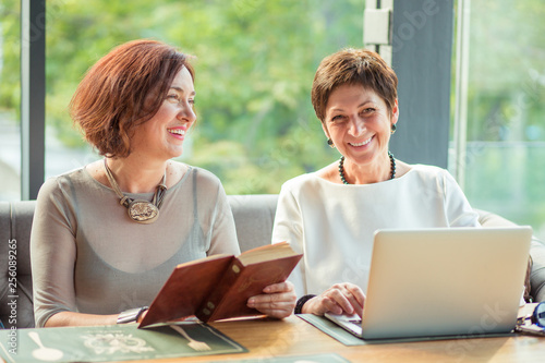 Beautiful aged women with laptop and book
