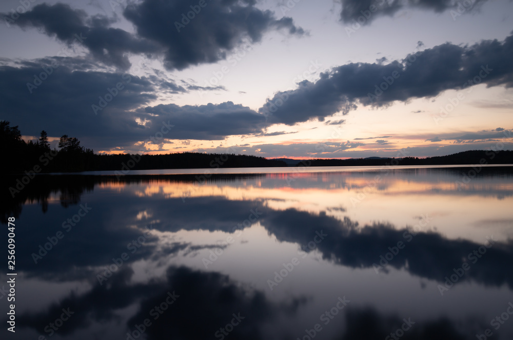 Calm lake in sweden at sunset with clouds reflecting in the water