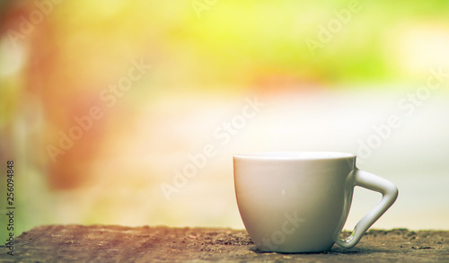 Ceramic coffee cup on old wood with summer nature green and yellow background