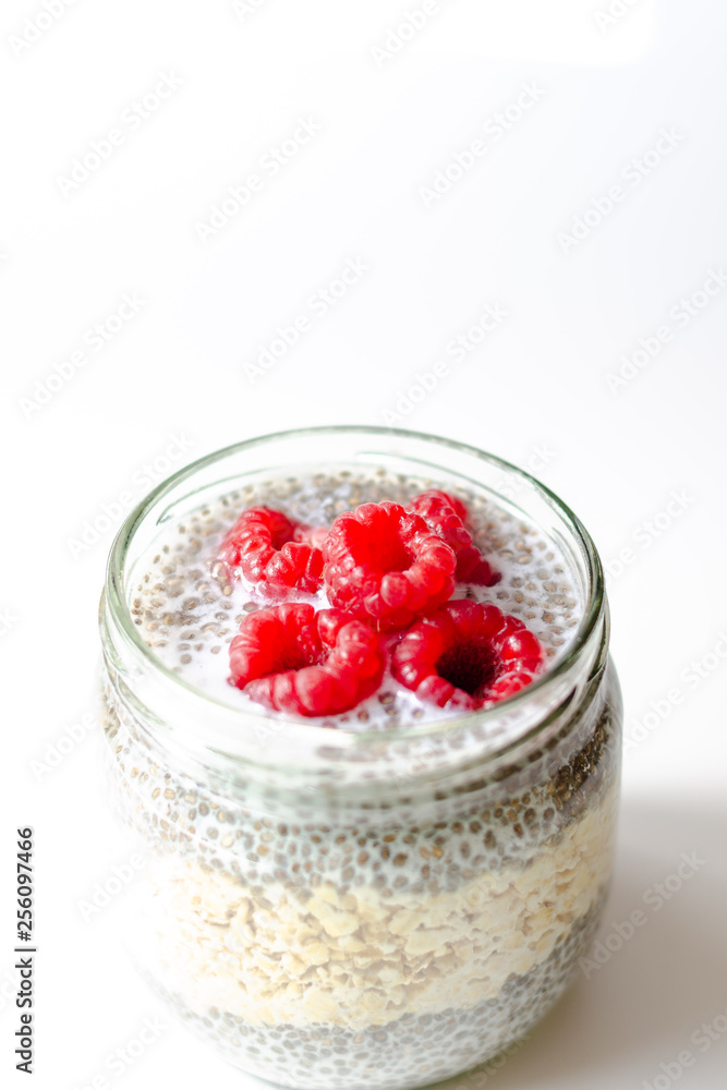 Oat pudding jar and chia seeds with raspberries on white background Oat pudding jar and chia seeds with raspberries on white background