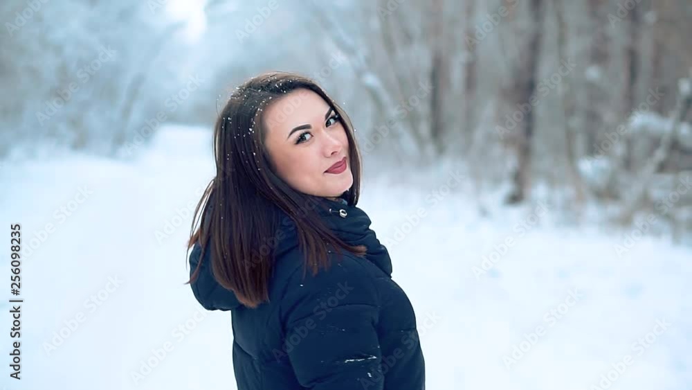 A beautiful young girl enjoys a winter walk in the cold snowy forest. She's posing for the camera, Christmas weekend. A beautiful young girl enjoys a winter walk in the cold snowy forest. She's posing for the camera, Christmas weekend.