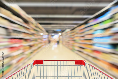 shopping cart in supermarket aisle with product shelves interior defocused blur background