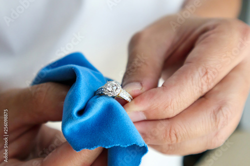 Jeweller hand polishing and cleaning jewelry diamond ring with micro fiber fabric photo