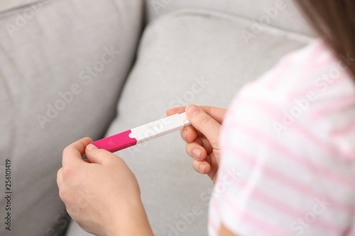 Young woman with pregnancy test indoors, closeup. Gynecology and childbirth
