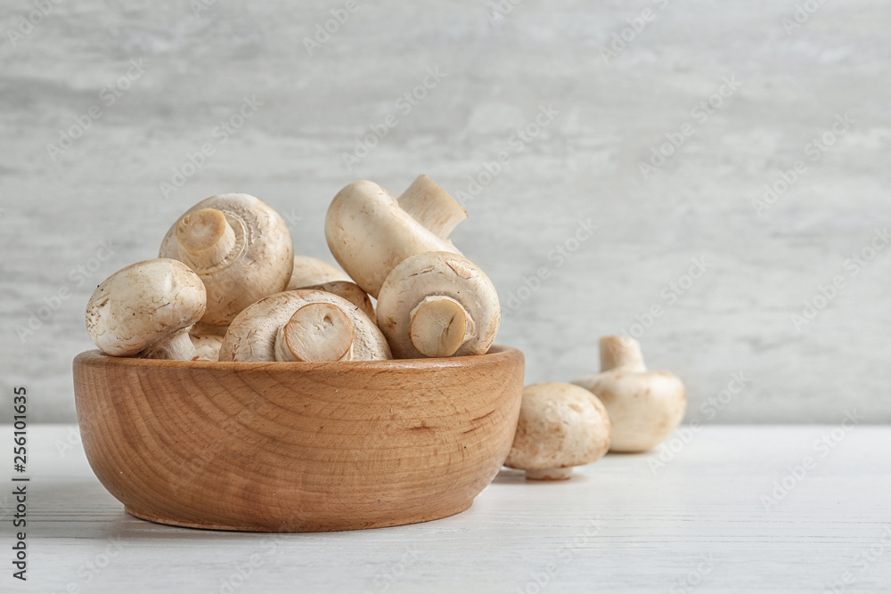 Bowl with fresh champignon mushrooms on wooden table, space for text Bowl with fresh champignon mushrooms on wooden table, space for text