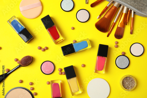 Flat lay composition with bottles of nail polish and different cosmetics on color background
