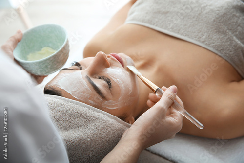 Cosmetologist applying mask on client's face in spa salon photo