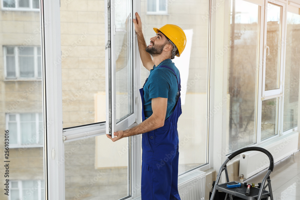 Construction worker installing plastic window in house Construction worker installing plastic window in house
