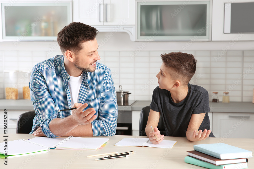 Dad helping his son with homework in kitchen Dad helping his son with homework in kitchen