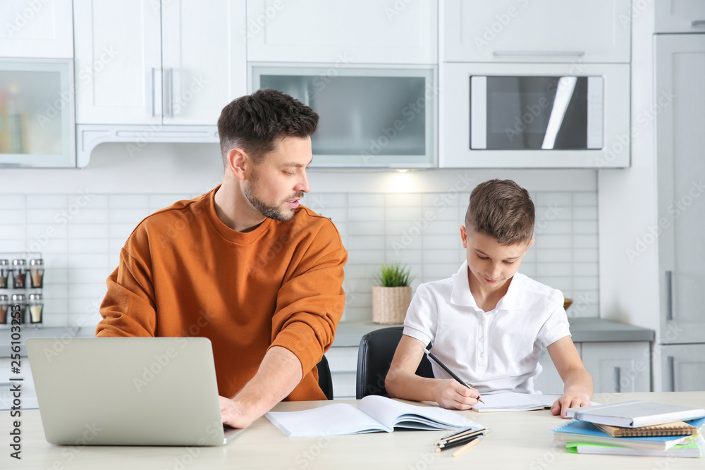 Dad helping his son with homework in kitchen Dad helping his son with homework in kitchen