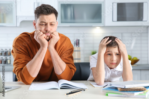 Dad helping his son with difficult homework assignment in kitchen