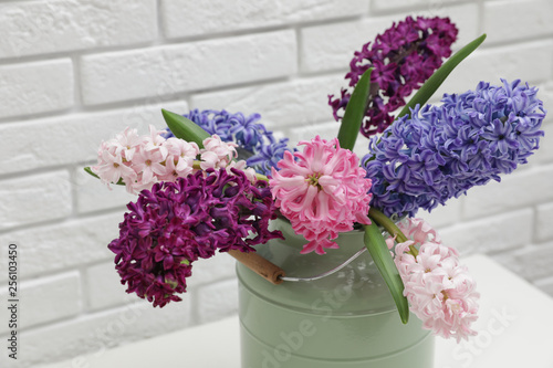 Beautiful hyacinths in metal can on table against brick wall. Spring flowers