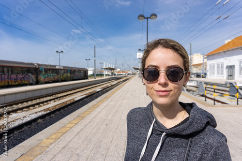 Pretty young woman waiting for train outside at train station
