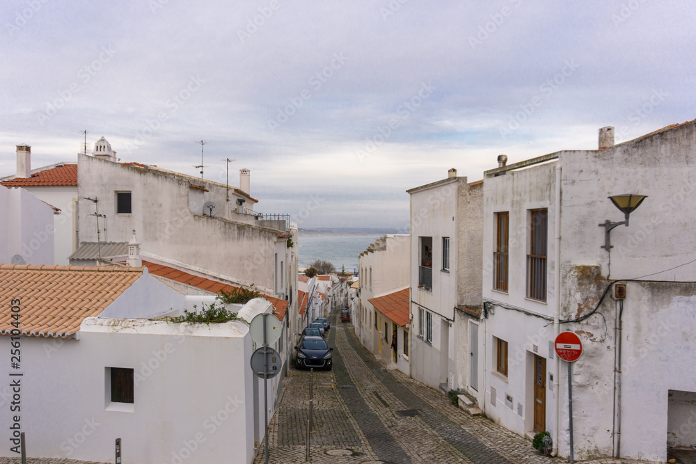 Car lined street in Lagos, Portugal with beach in background