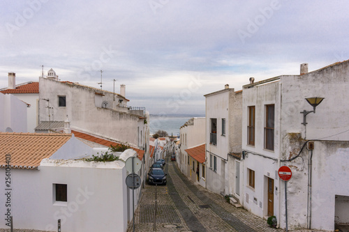 Car lined street in Lagos, Portugal with beach in background © grenierb
