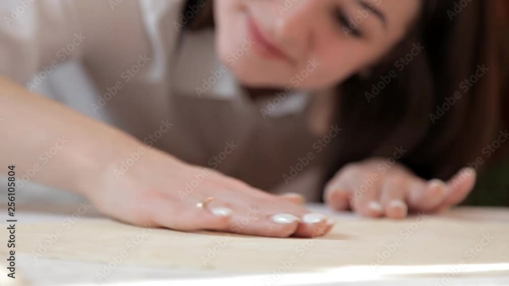 The girl smooths the dough with her hands on the table, making sure that it is even The girl smooths the dough with her hands on the table, making sure that it is even